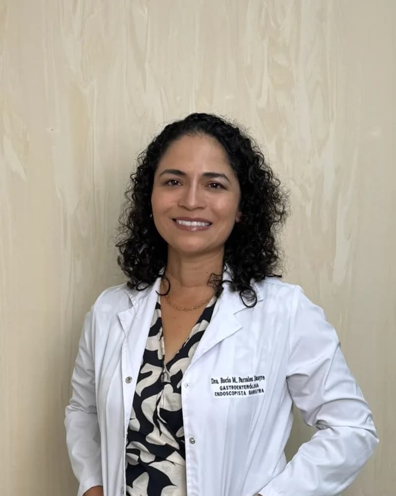 Dra. Rocío M. Parrales, gastroenteróloga de Almavia, sonriendo con bata blanca frente a una pared clara